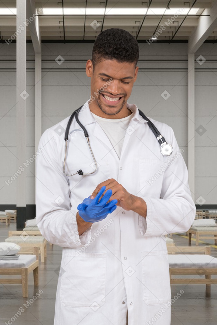 A male doctor putting on a medical glove