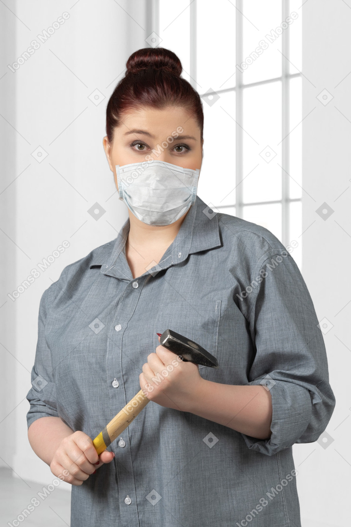 Woman in face mask holding a hammer