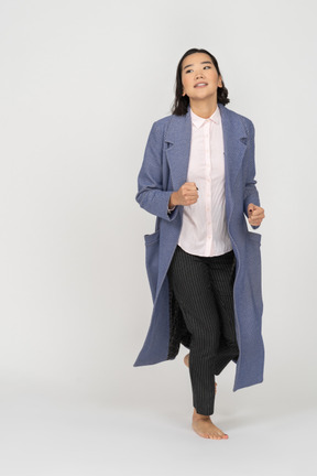 Young woman in coat jogging
