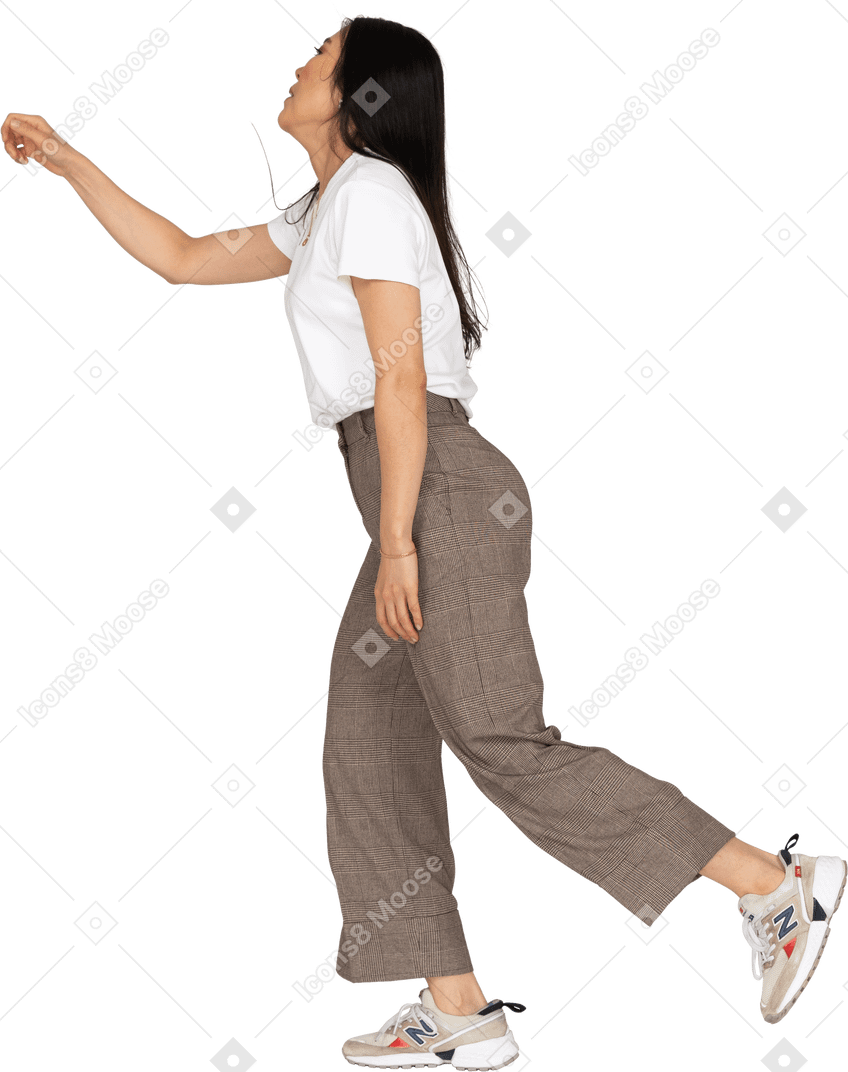 Vista laterale di una giovane donna che balla in calzoni e t-shirt protese la mano