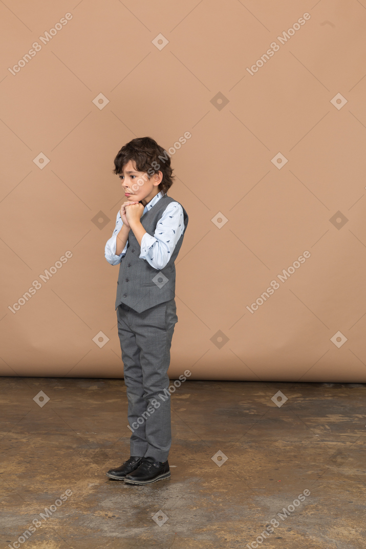 Вид сбоку задумчивого мальчика в сером костюме