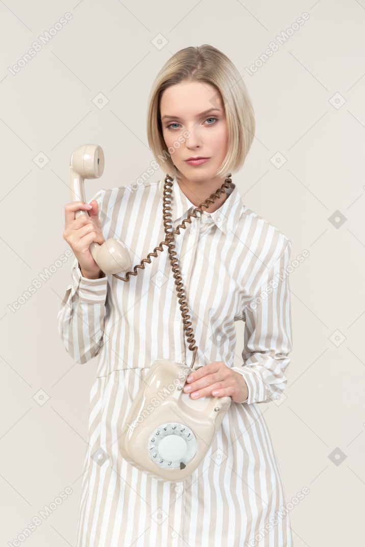 Serious looking young woman holding phone cord over the neck