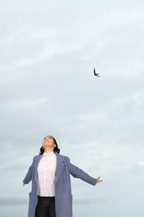 A woman with her arms outstretched on a cloudy day