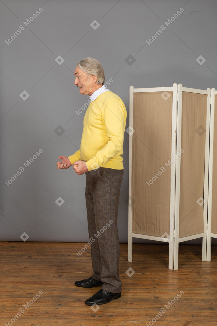 Side view of an impatient old man clenching fists