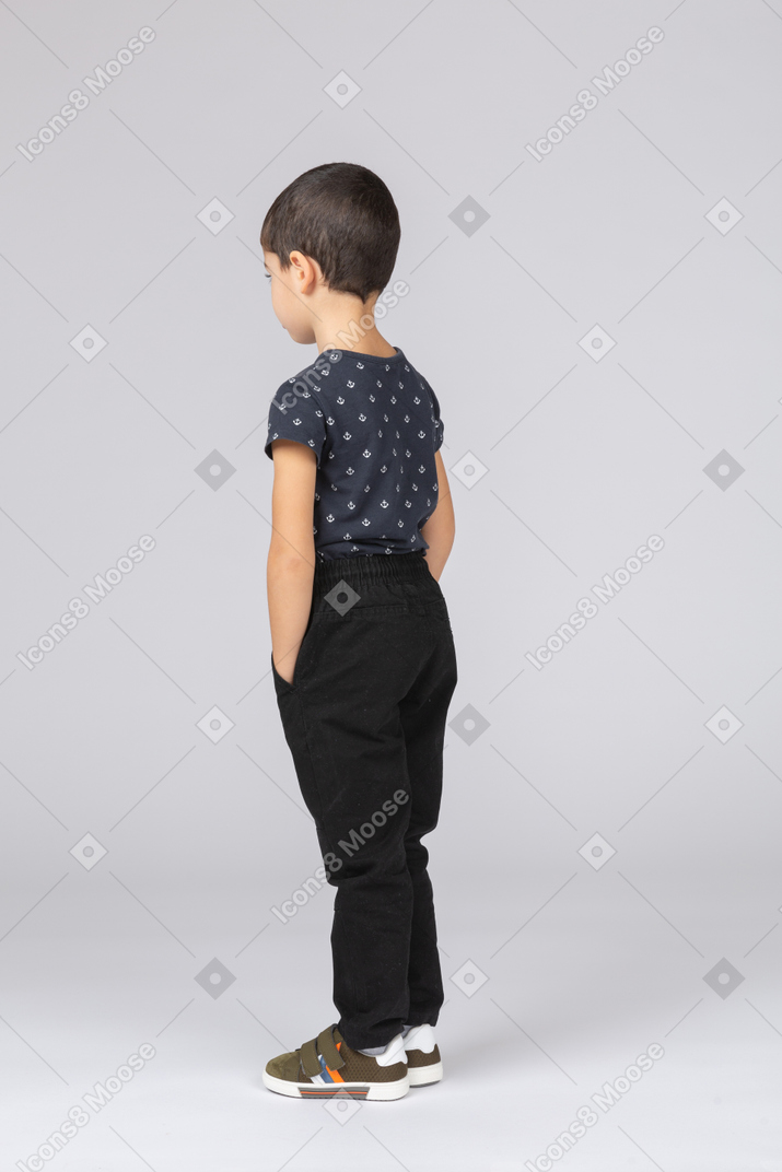 Side view of a cute boy standing with hands in pockets