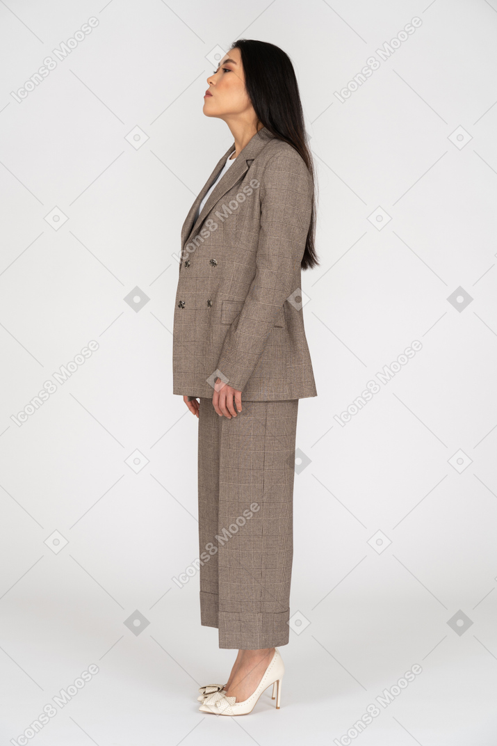 Side view of a young lady in brown business suit raising head