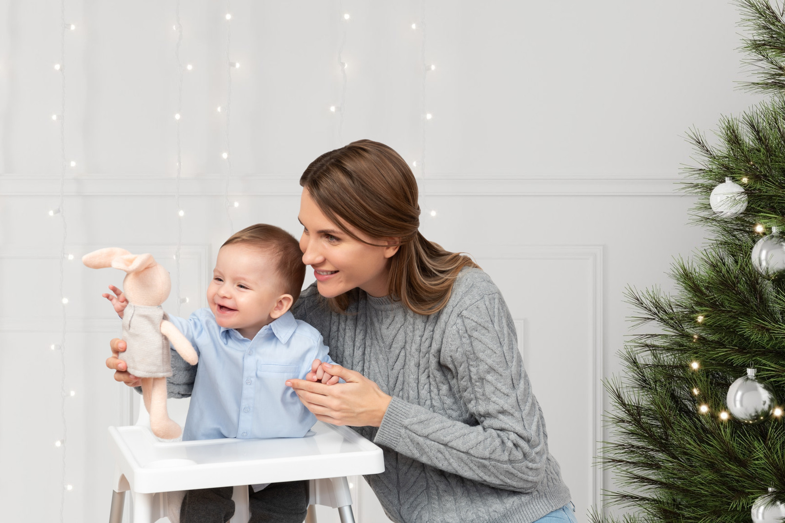 A mother and her baby are playing with a christmas tree