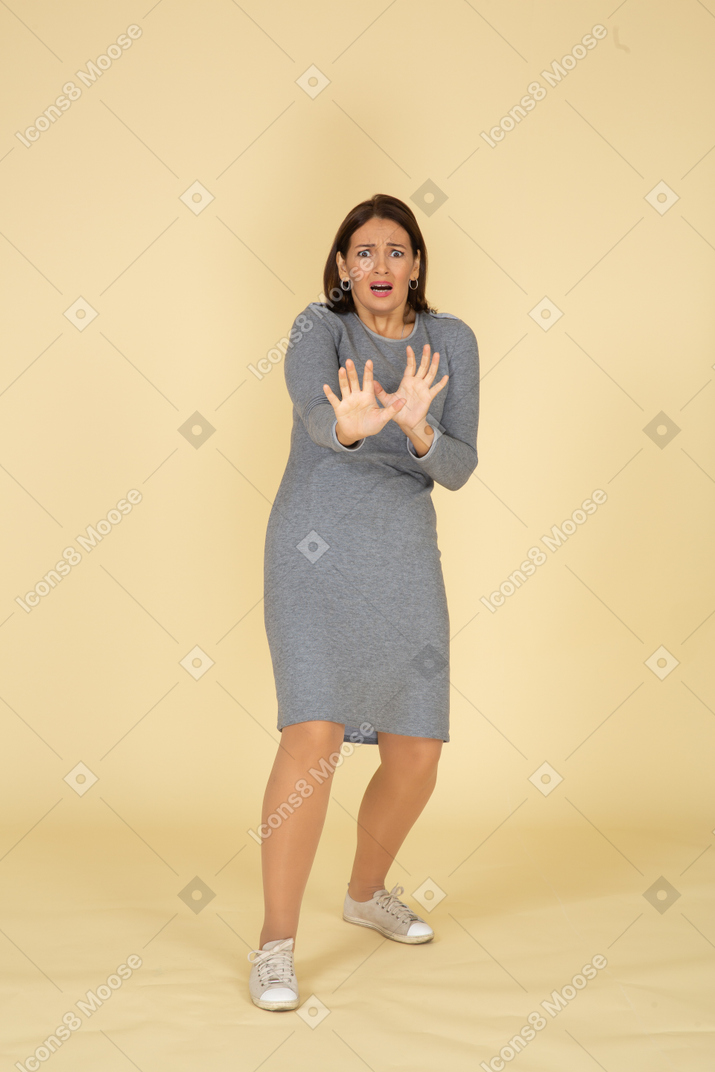 Vista frontale di una donna spaventata in abito grigio