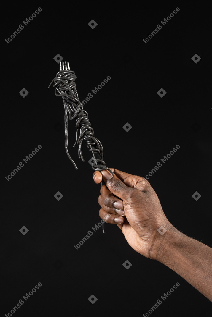 Close-up of a human hand holding black pasta