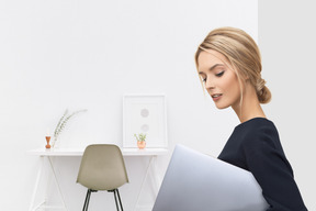 Woman holding laptop in front of her workplace