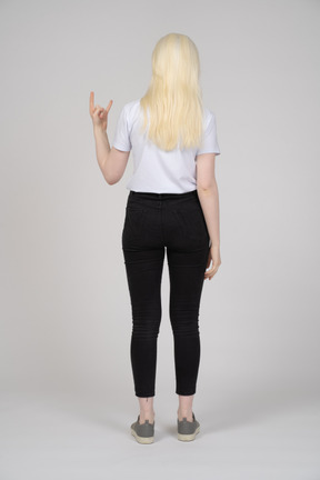Vista traseira de uma jovem mostrando chifres de mão
