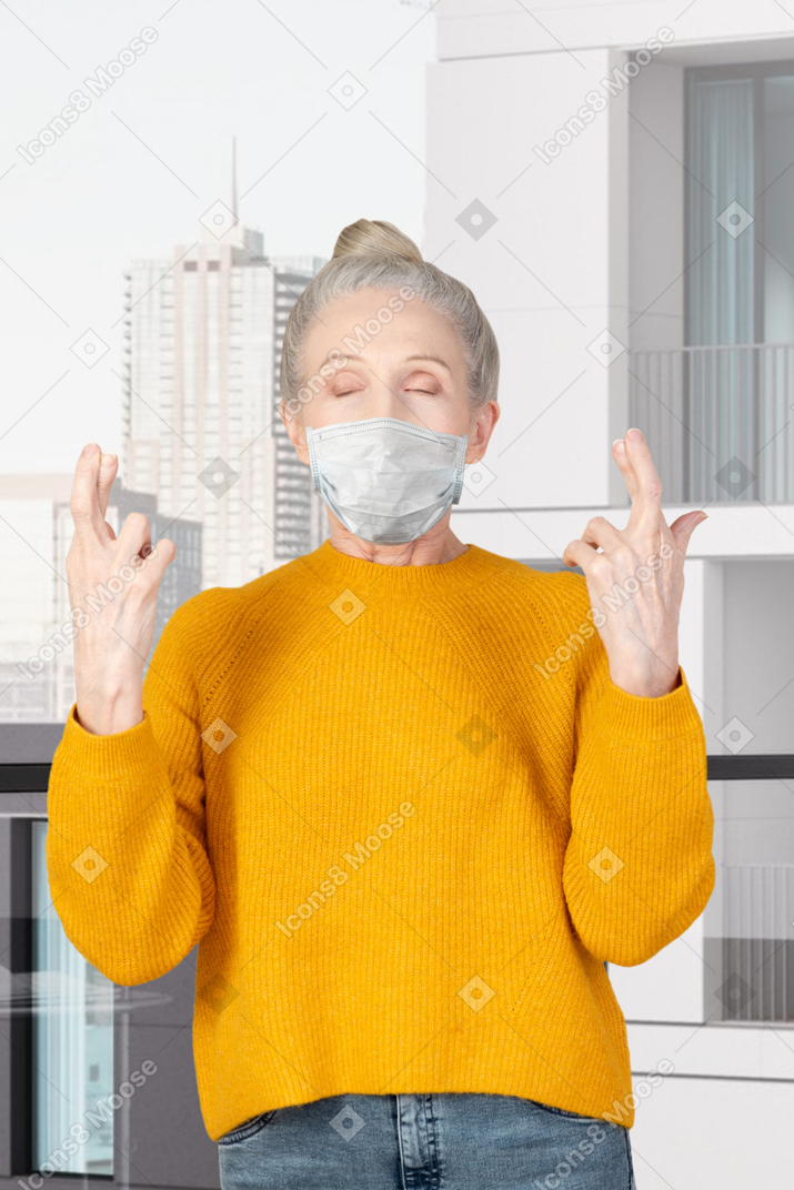 Elderly lady standing with her fingers crossed