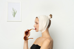 Vue latérale d'une femme avec un bandage sur la tête tenant des lunettes de soleil
