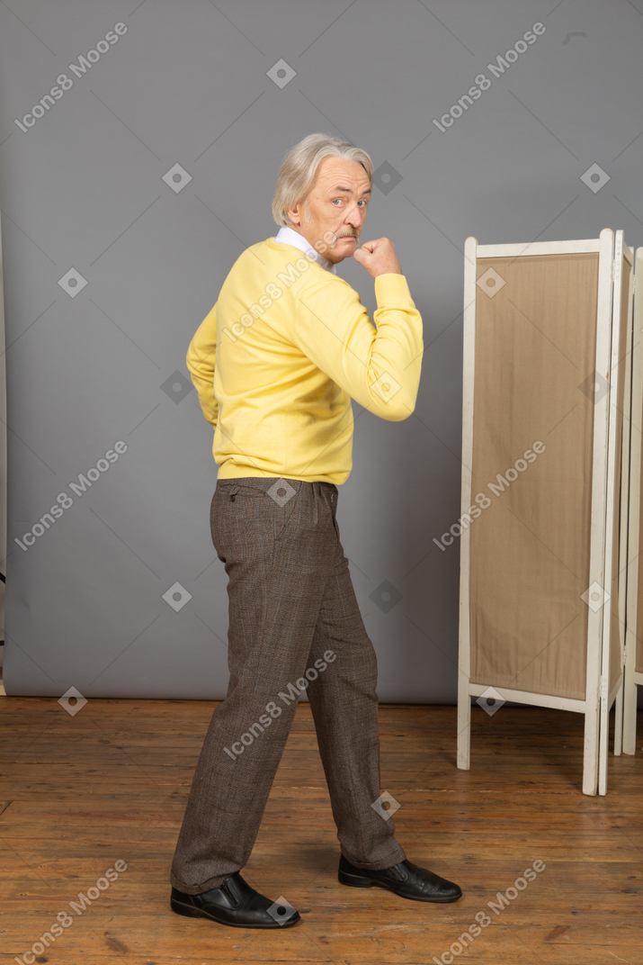 Side view of an old man looking at camera while demonstrating his strength