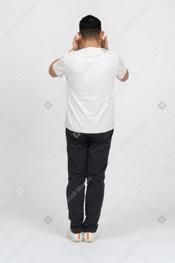 Homem em roupas casuais em pé de costas para a câmera e cobrindo o rosto com as mãos
