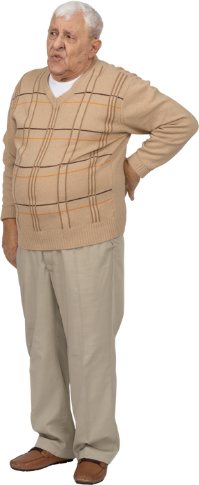 Vista frontal de un anciano con ropa informal de pie con la mano en la espalda