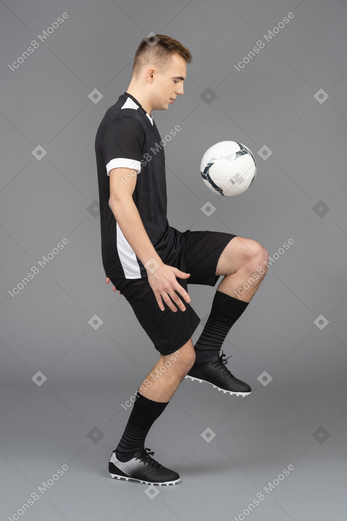 Vista lateral de um jogador de futebol chutando uma bola