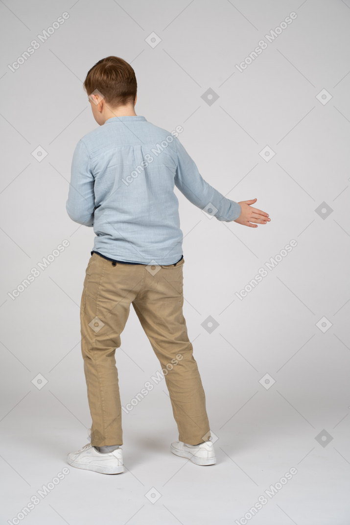 Boy in blue shirt and khaki pants pointing to the right