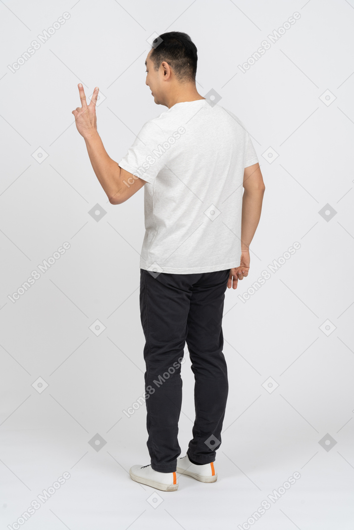 Dreiviertelansicht eines mannes in freizeitkleidung mit v-zeichen