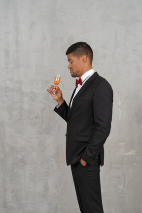 Vue latérale d'un homme peu impressionné tenant un verre de champagne