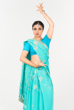 Joven mujer india en sari azul de pie en posición de baile