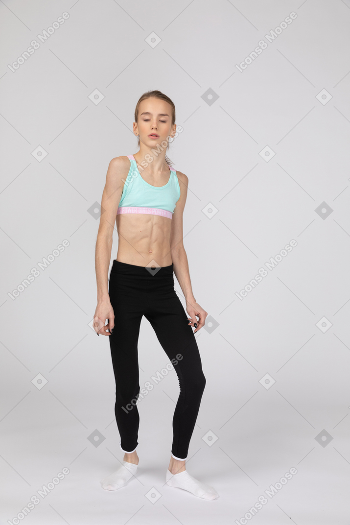 Three-quarter view of a teen girl in sportswear standing with her eyes closed