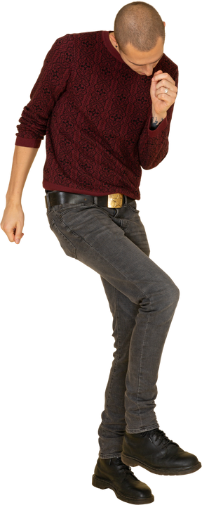 跳舞的年轻男子，穿着红色套头衫抬腿的前视图