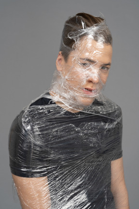 Close up of a young man wrapped in plastic