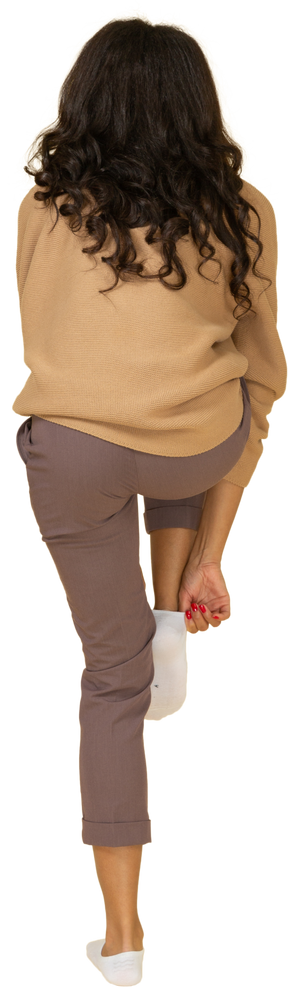 Vista traseira de uma jovem mulher de pele escura cansada calçando uma meia