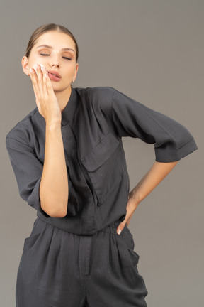 Front view of a young woman in a jumpsuit removing make-up