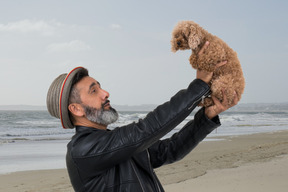 A man holding a little dog on the beach