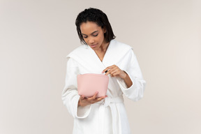 Black woman in white bathrobe going about her morning routine