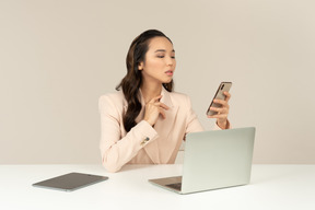 Empleado de oficina femenino asiático comprobando teléfono