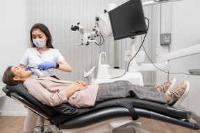 Toute la longueur d'une femme dentiste extrayant la dent de son patient dans une armoire d'hôpital