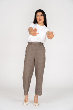 Vista frontale di una giovane donna in calzoni protese le mani