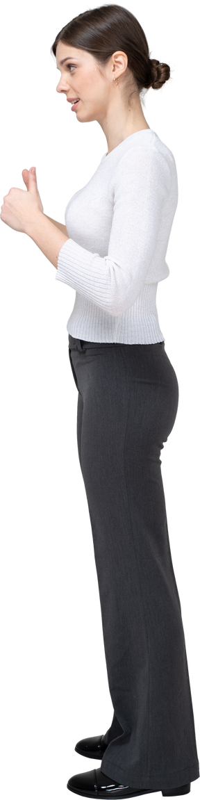 Vista laterale di una donna in pantaloni neri e camicetta bianca che mostra i pollici in su