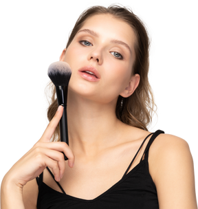 Front view of a sensual young woman holding a make-up brush
