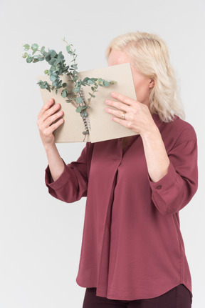 A nice-looking middle-aged blonde woman in a burgundy shirt and a craft notebook in her hand