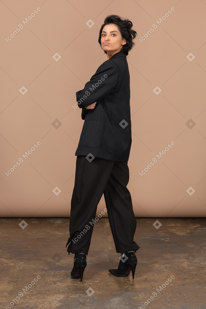 Corpo inteiro de uma mulher de negócios em um terno preto olhando para a câmera enquanto faz beicinho