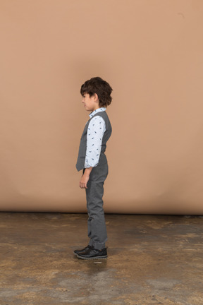Cute boy in grey suit standing in profile