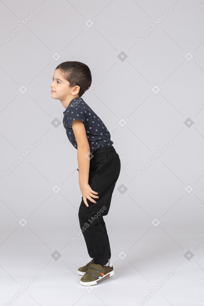 Side view of a cute boy in casual clothes bending down