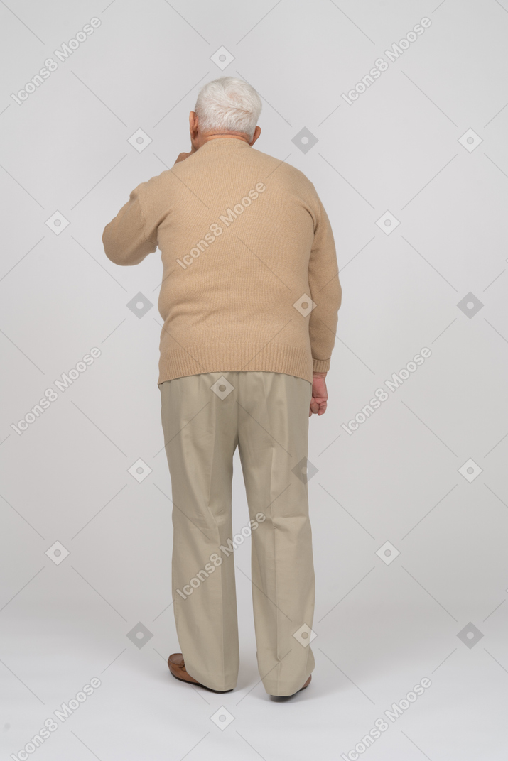 Shhhジェスチャーをしているカジュアルな服を着た老人の背面図