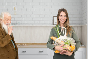 A woman holding a bag of groceries next to an old man