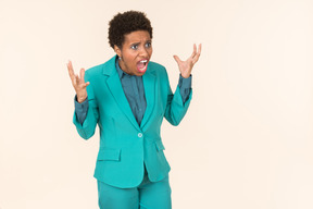 Black woman with a short haircut, wearing all blue, standing against a plain pastel background, looking emotional