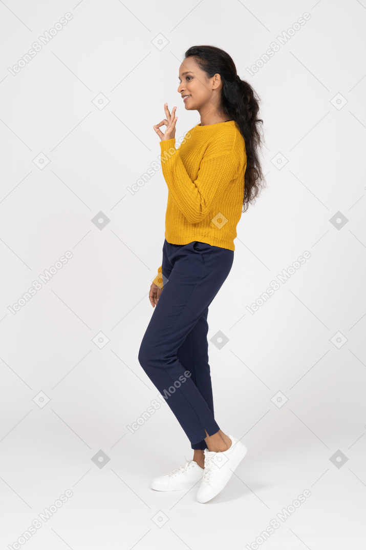 Side view of a girl in casual clothes showing ok sign