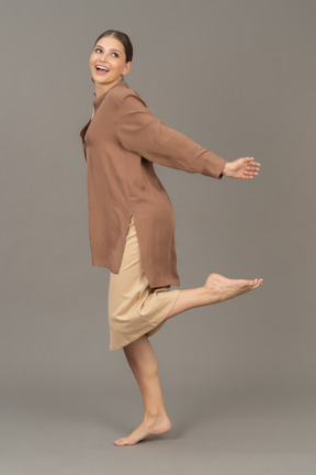 一名妇女赤脚站立并在空中抬起左腿的侧视图