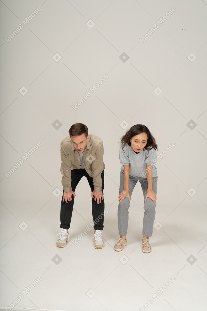 Powerless young man and woman standing with hands on knees