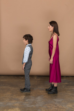 Femme en robe rouge et petit garçon debout de profil