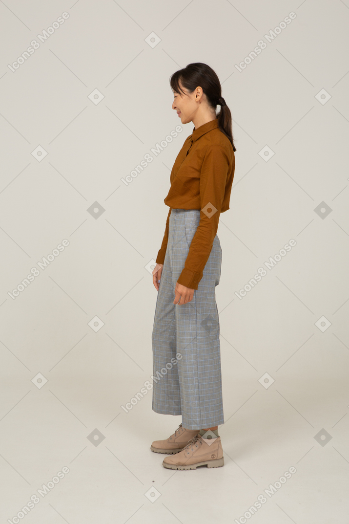 Vista lateral de uma jovem mulher asiática piscando em calça e blusa