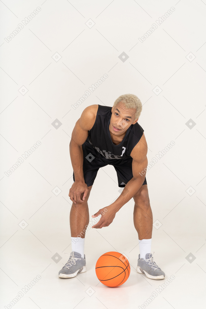 Front view of a young male basketball player touching ball